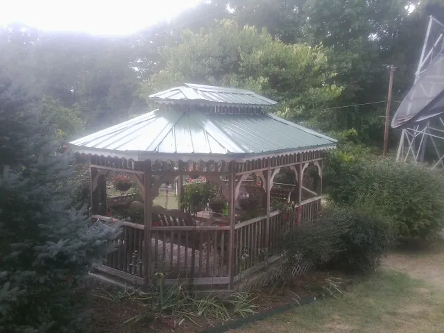Green metal roof on a backyard gazebo surrounded by garden beds in Monroe